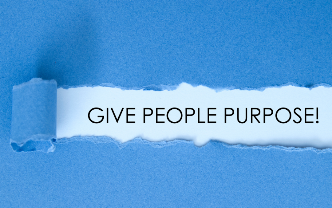 This is an image of the words typed out on a light blue piece of paper. They say ‘Give people purpose’ . Overlaid is a darker blue paper that has been torn to reveal the text underneath.